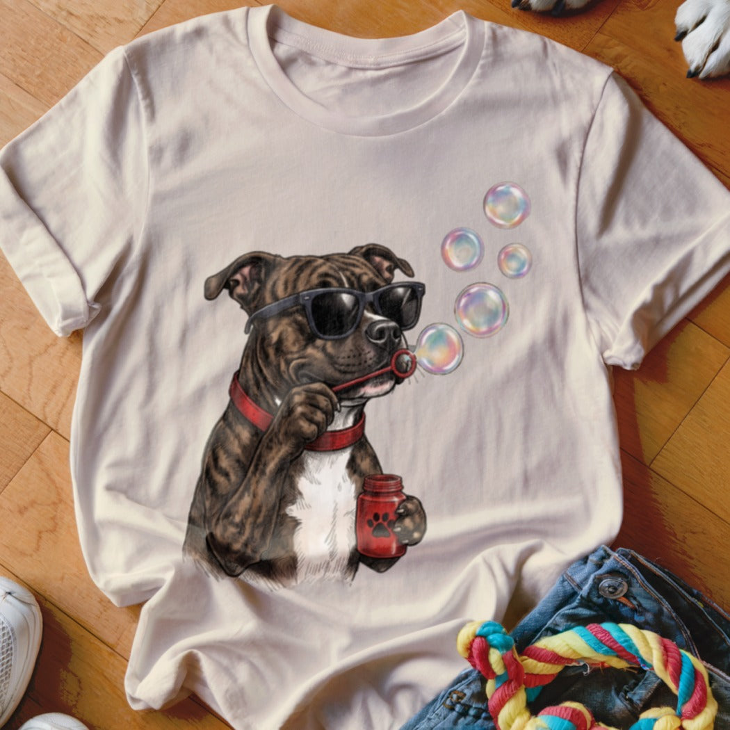 Beige t-shirt featuring a graphic of a brindle dog wearing sunglasses and blowing bubbles.