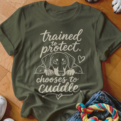 Olive green t-shirt with dog graphic and text "trained to protect, chooses to cuddle."