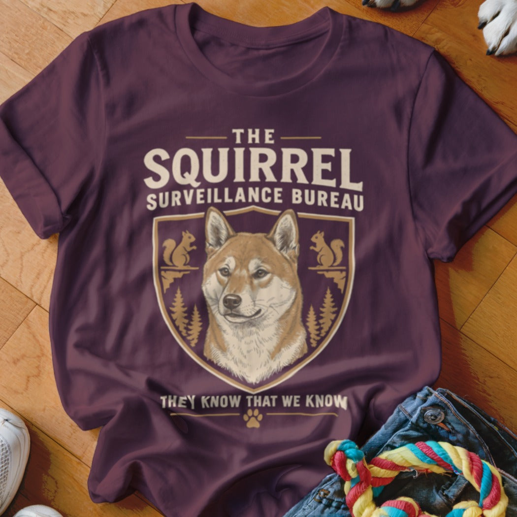 Maroon crewneck t-shirt featuring a Shiba Inu graphic and text reading The Squirrel Surveillance Bureau.