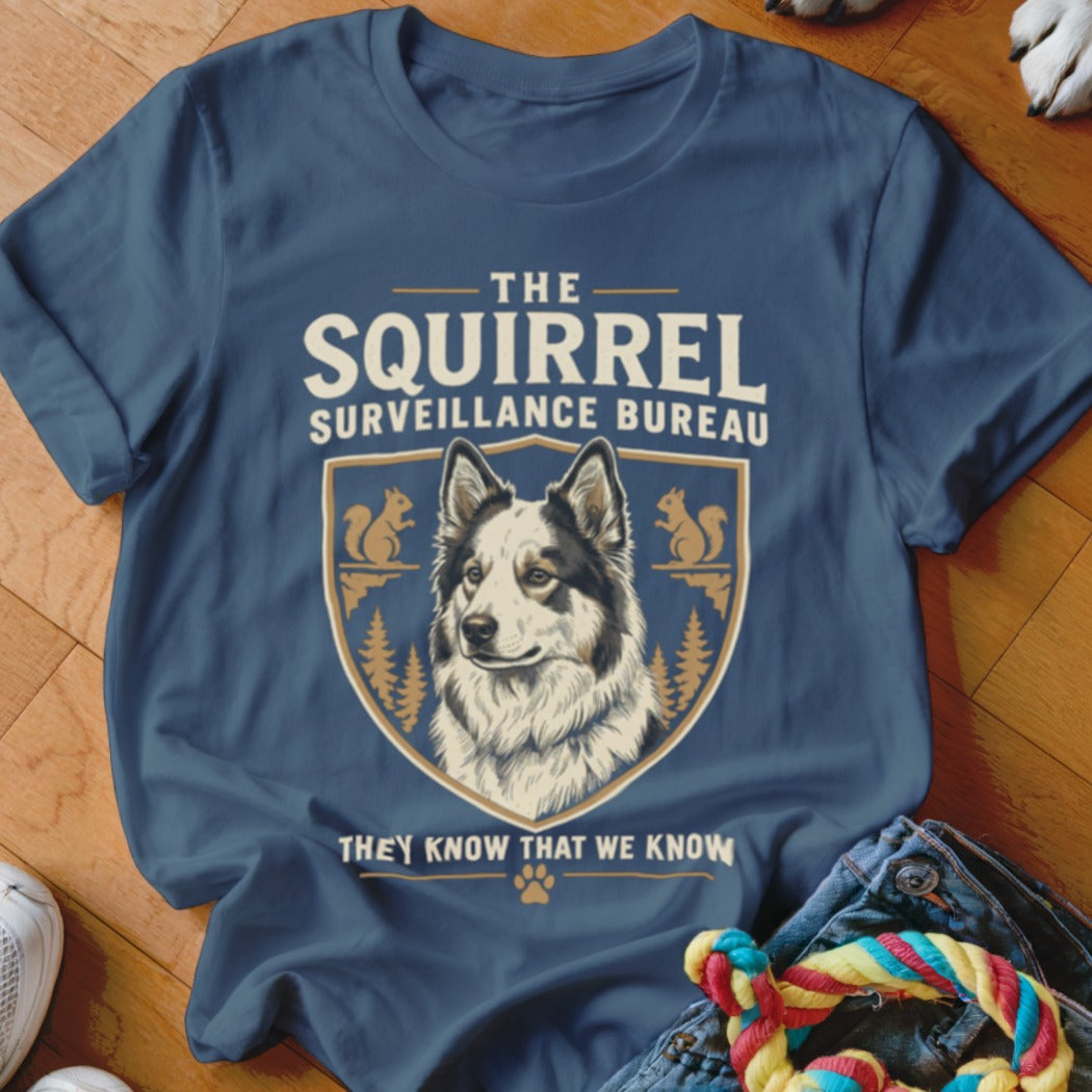 A dark blue t-shirt featuring a crest with a dog, squirrels, and the text The Squirrel Surveillance Bureau.
