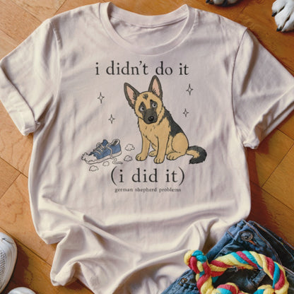 German Shepherd wearing a t-shirt with a dog and shoe graphic: "i didn't do it (i did it)".