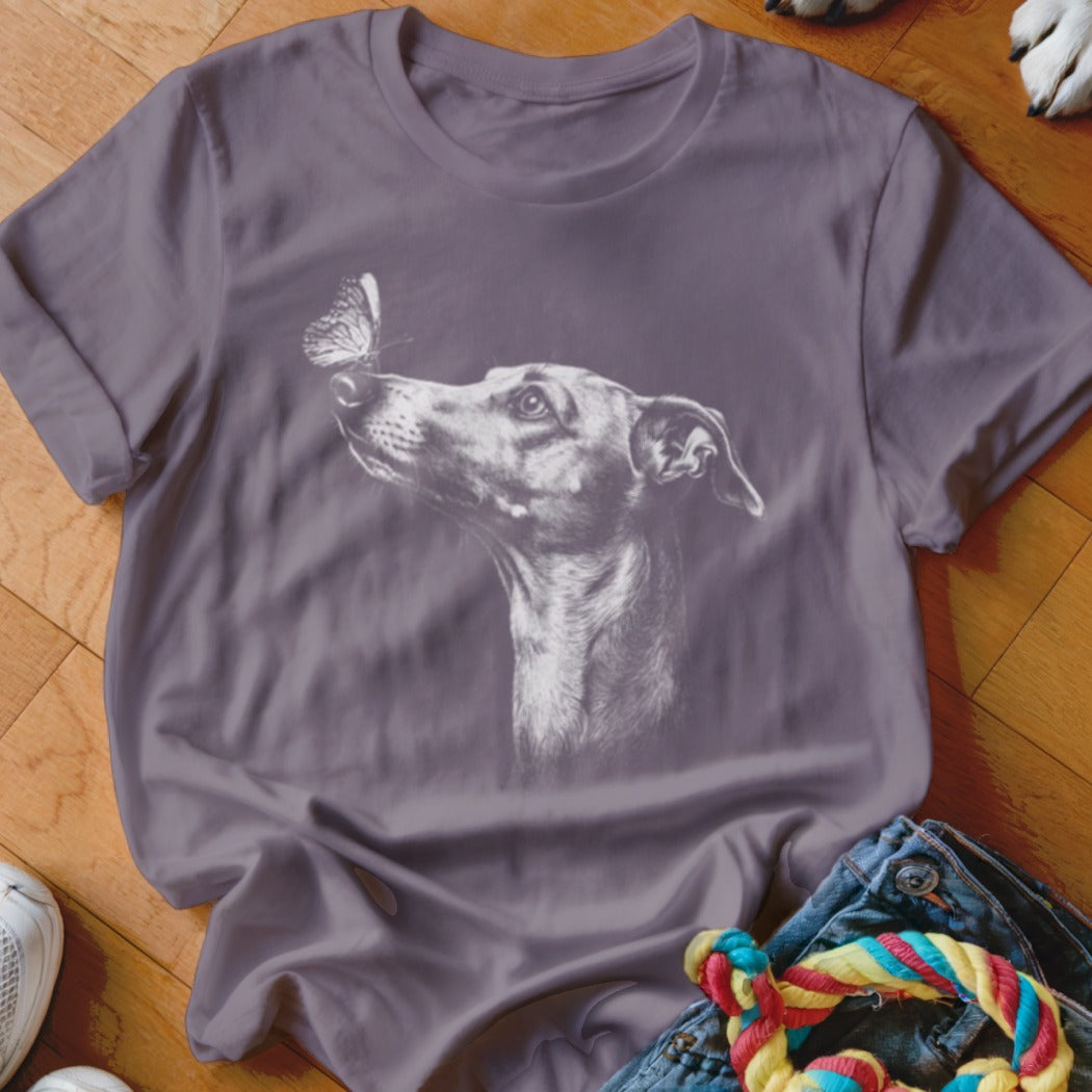 A grey crewneck t-shirt featuring a white line drawing of a dog looking at a butterfly on its nose.