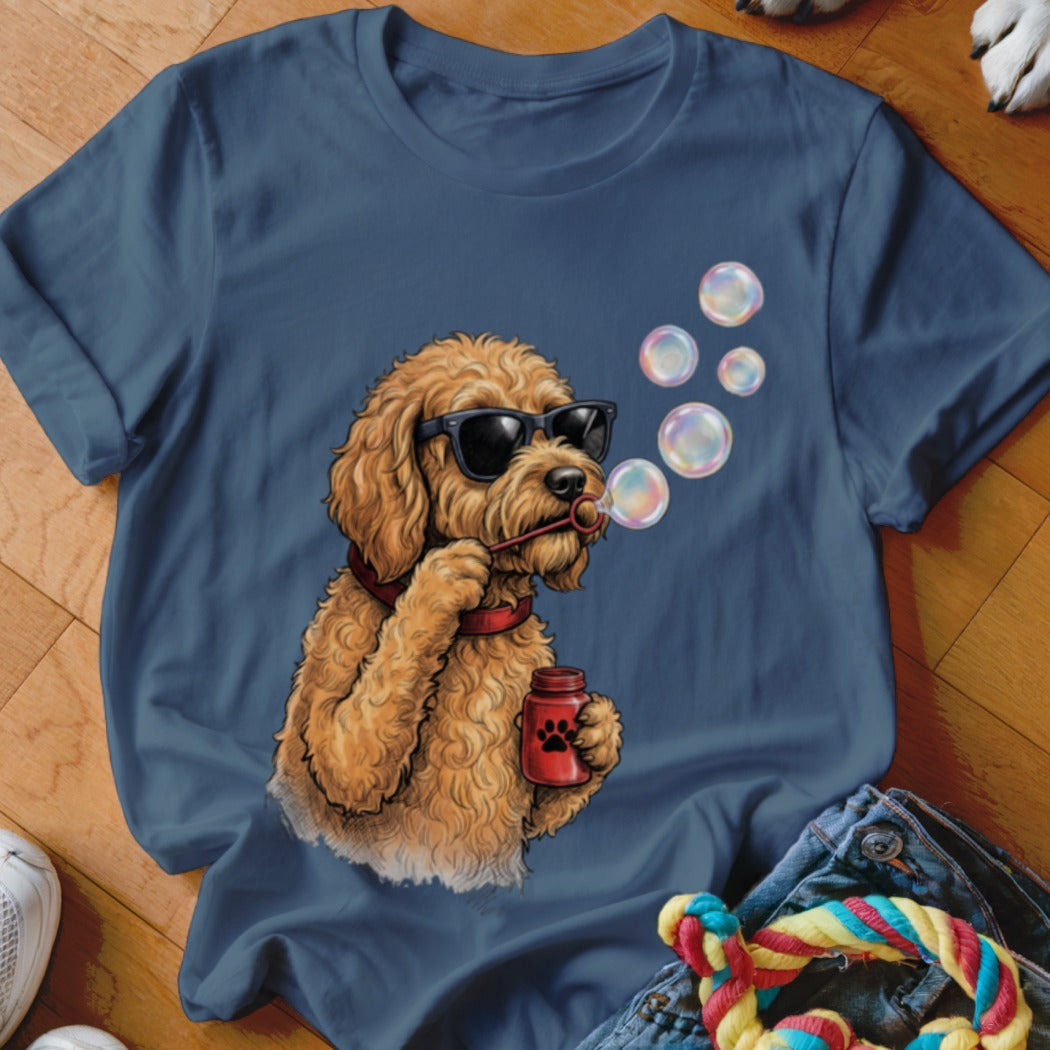 Blue t-shirt featuring an illustration of a fluffy golden dog wearing sunglasses and blowing bubbles.