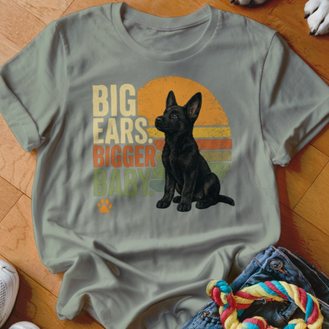 Black German Shepherd puppy sitting with "BIG EARS. BIGGER BABY." text.