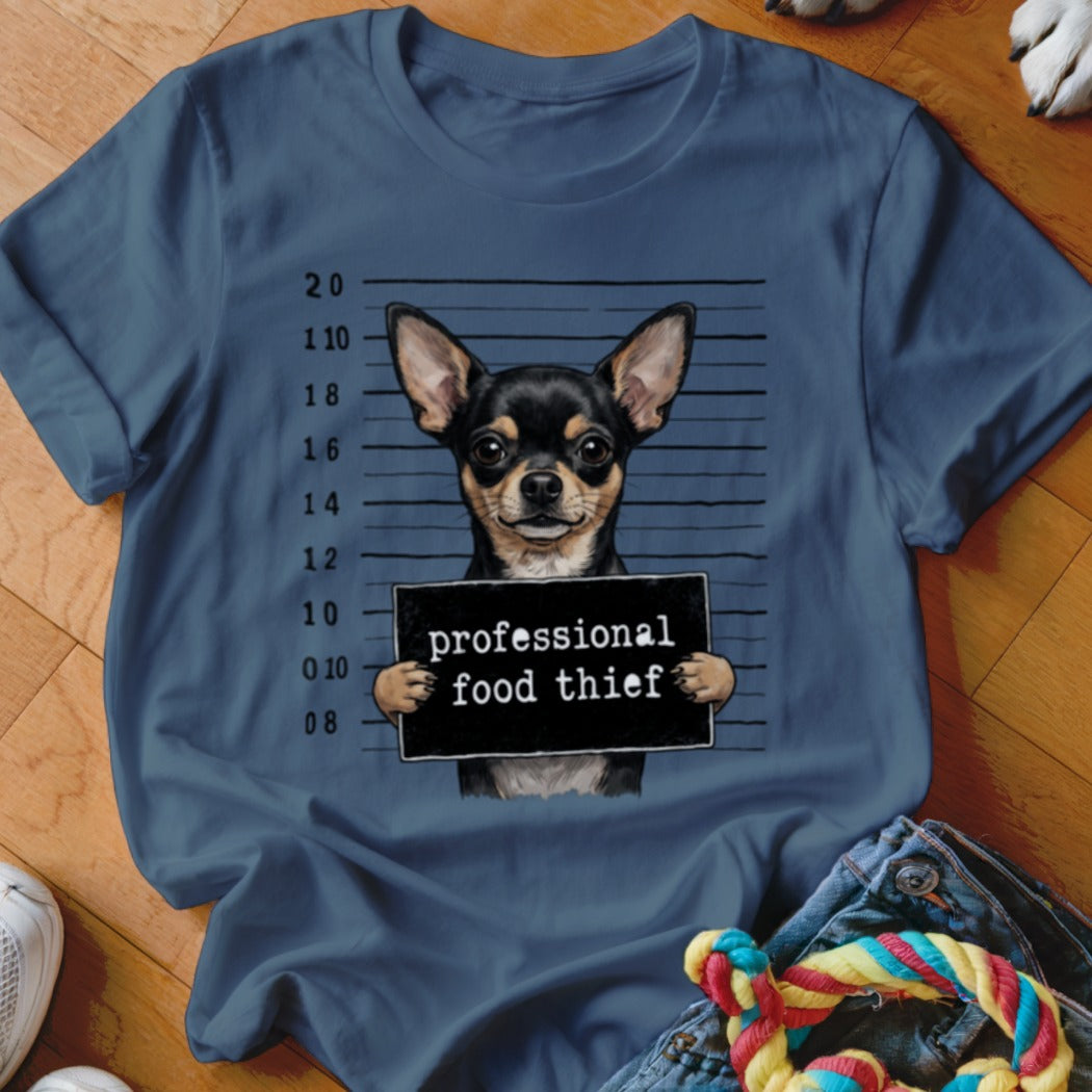 Chihuahua in mugshot holding a sign that reads "professional food thief".