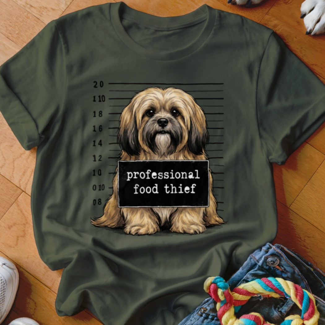 Shih Tzu dog with a "professional food thief" sign in mugshot style.