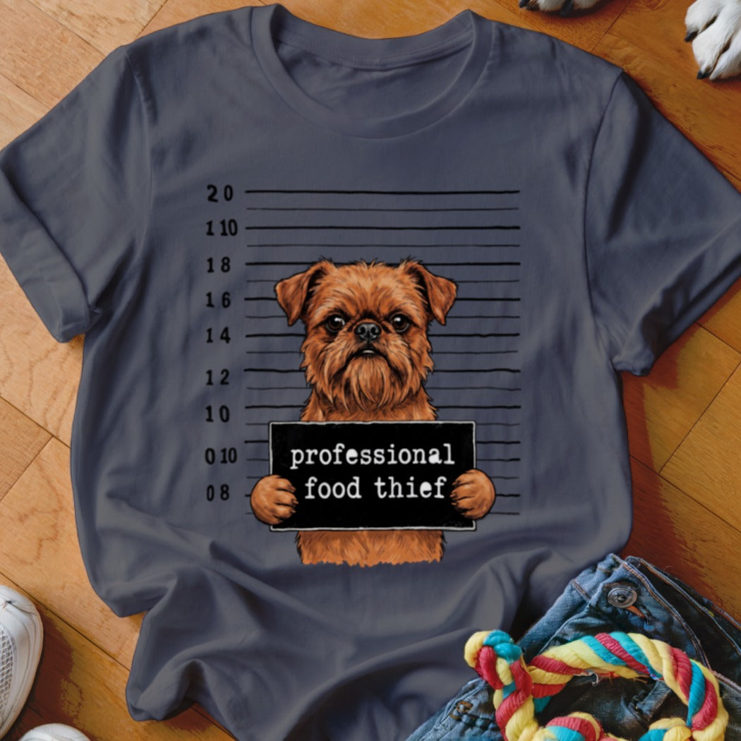 Brown dog with "professional food thief" sign on a mugshot background.
