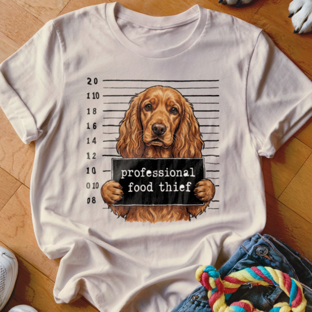 Cocker spaniel mugshot with sign reading "professional food thief".