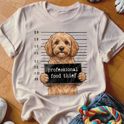 Dog mugshot with "professional food thief" sign on a t-shirt.