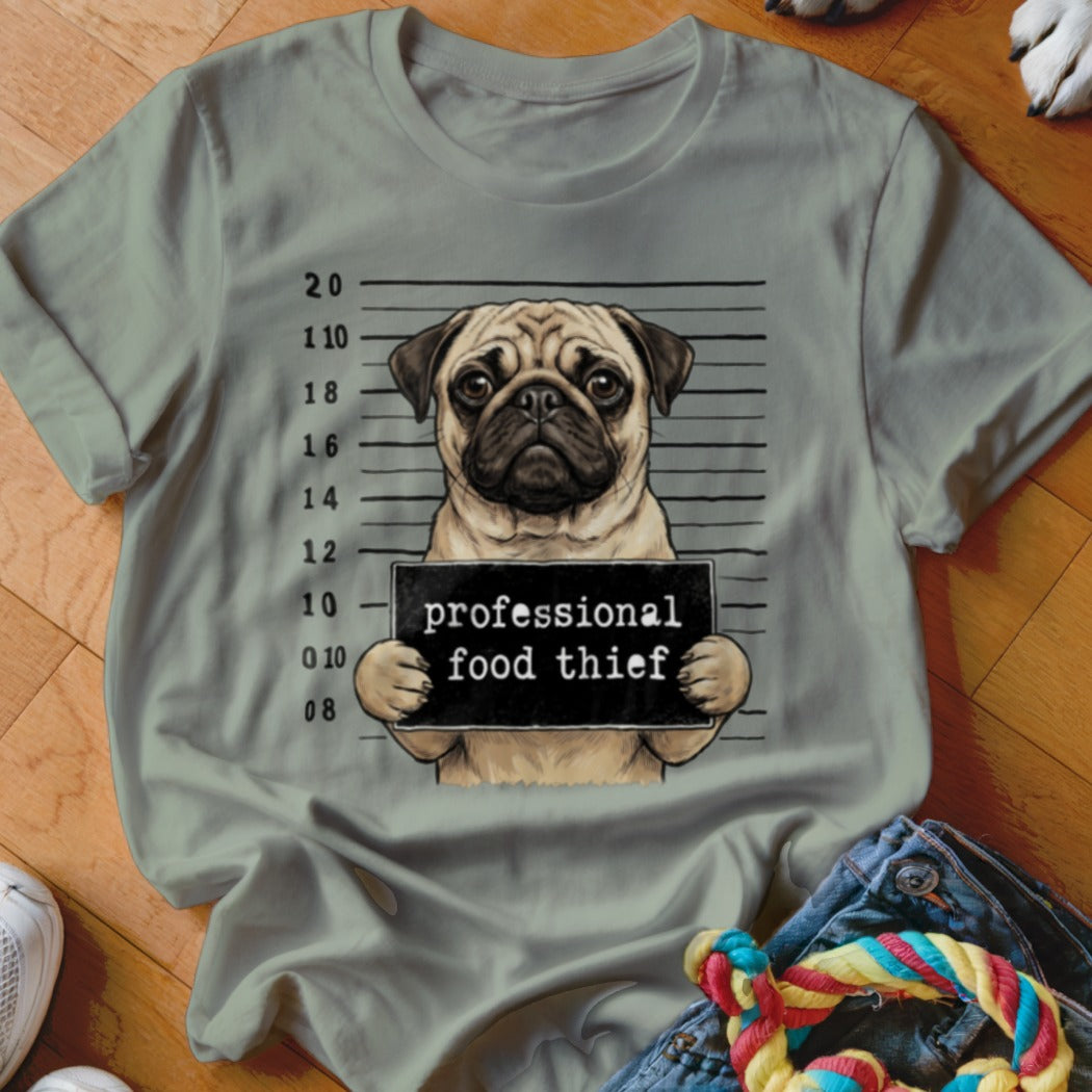 Pug mugshot with "professional food thief" sign on a gray t-shirt.