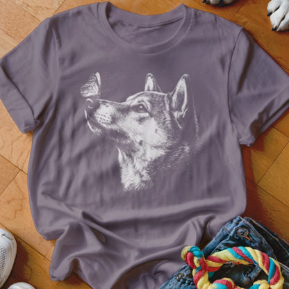 A grey t-shirt featuring a white graphic of a wolf looking up at a butterfly on its nose.