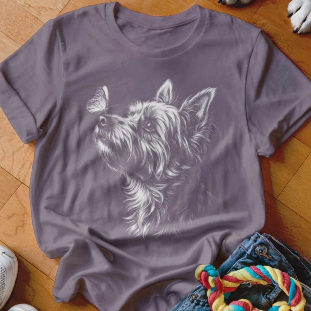 A purple crewneck t-shirt featuring a white line drawing of a terrier dog looking up at a butterfly.