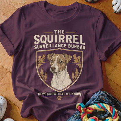 A dark plum t-shirt featuring a Jack Russell Terrier graphic and text reading The Squirrel Surveillance Bureau.