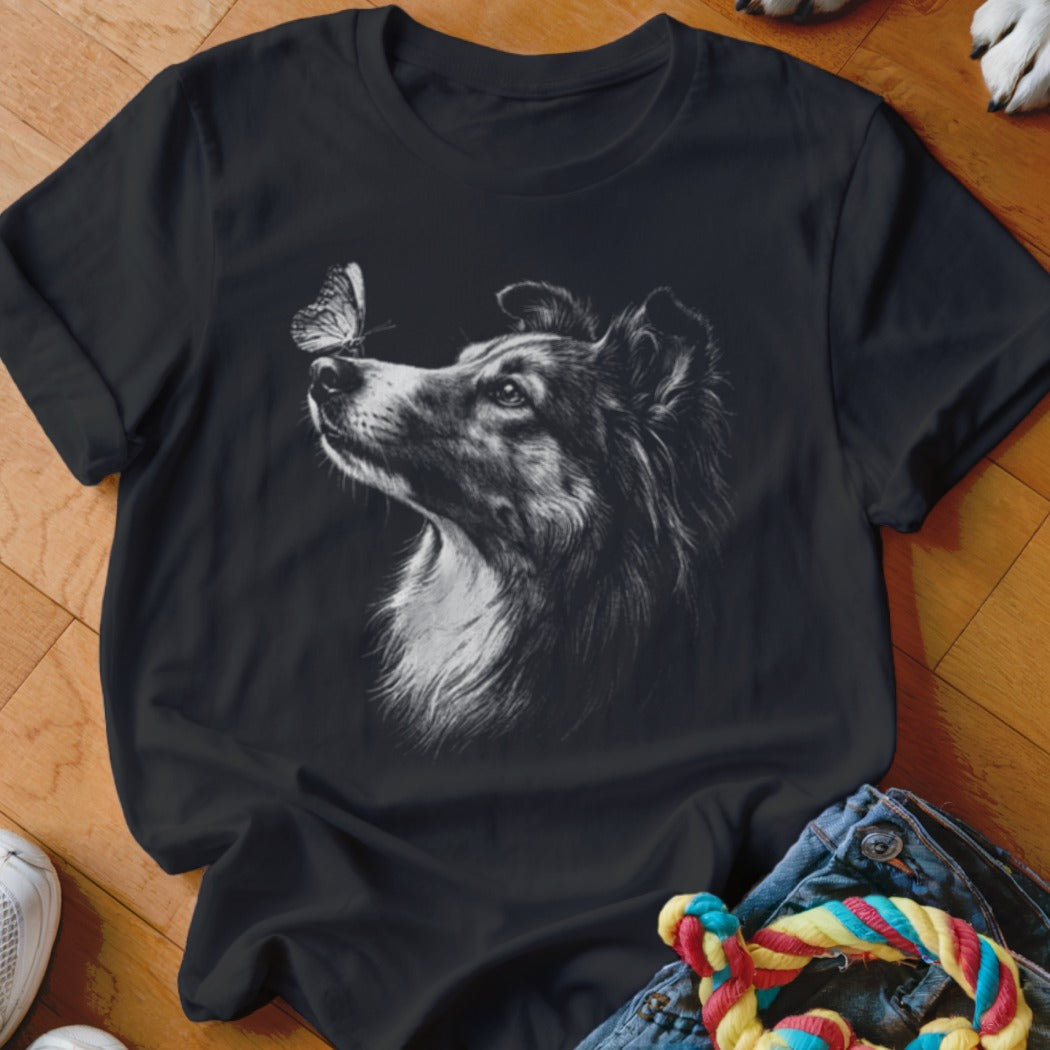 Black t-shirt featuring a white graphic of a collie looking at a butterfly on its nose.