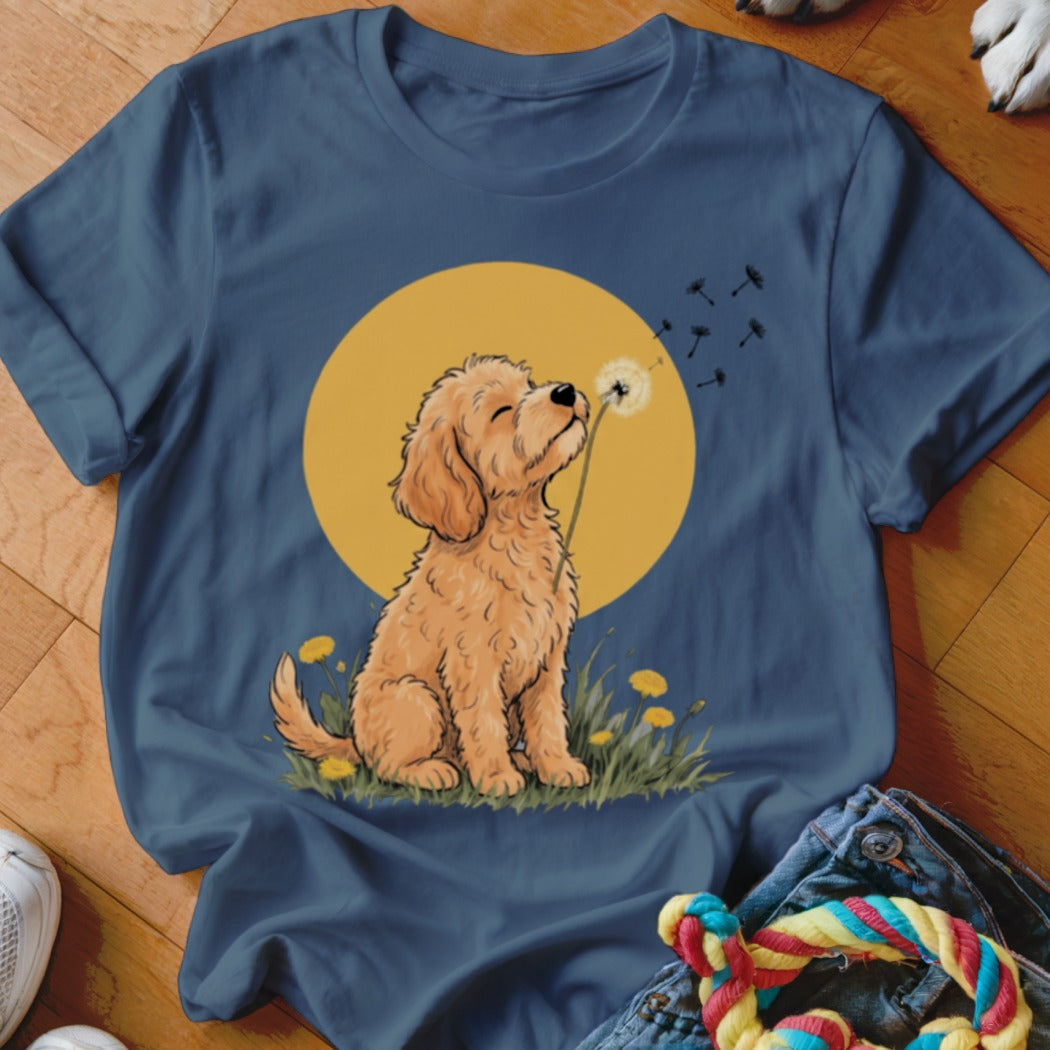 A blue crewneck t-shirt featuring a graphic of a golden puppy blowing a dandelion against a yellow circle.