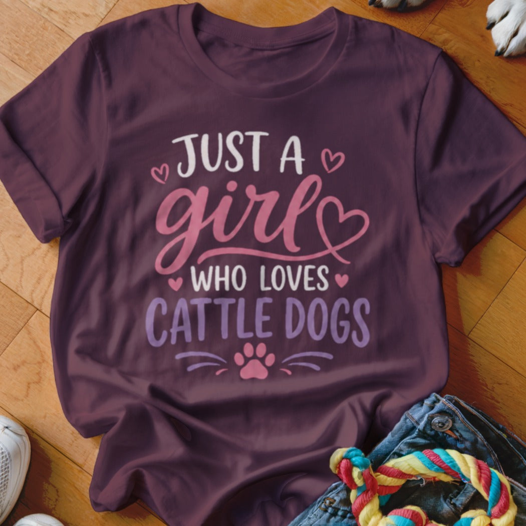 Burgundy t-shirt with text "JUST A girl WHO LOVES CATTLE DOGS" and paw print.