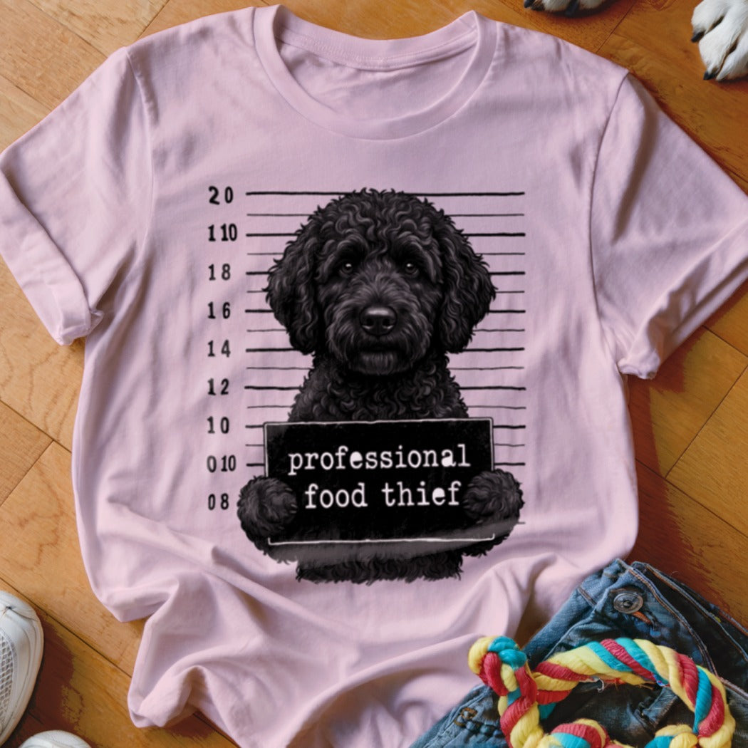 Pink t-shirt graphic of a black dog holding a "professional food thief" sign.