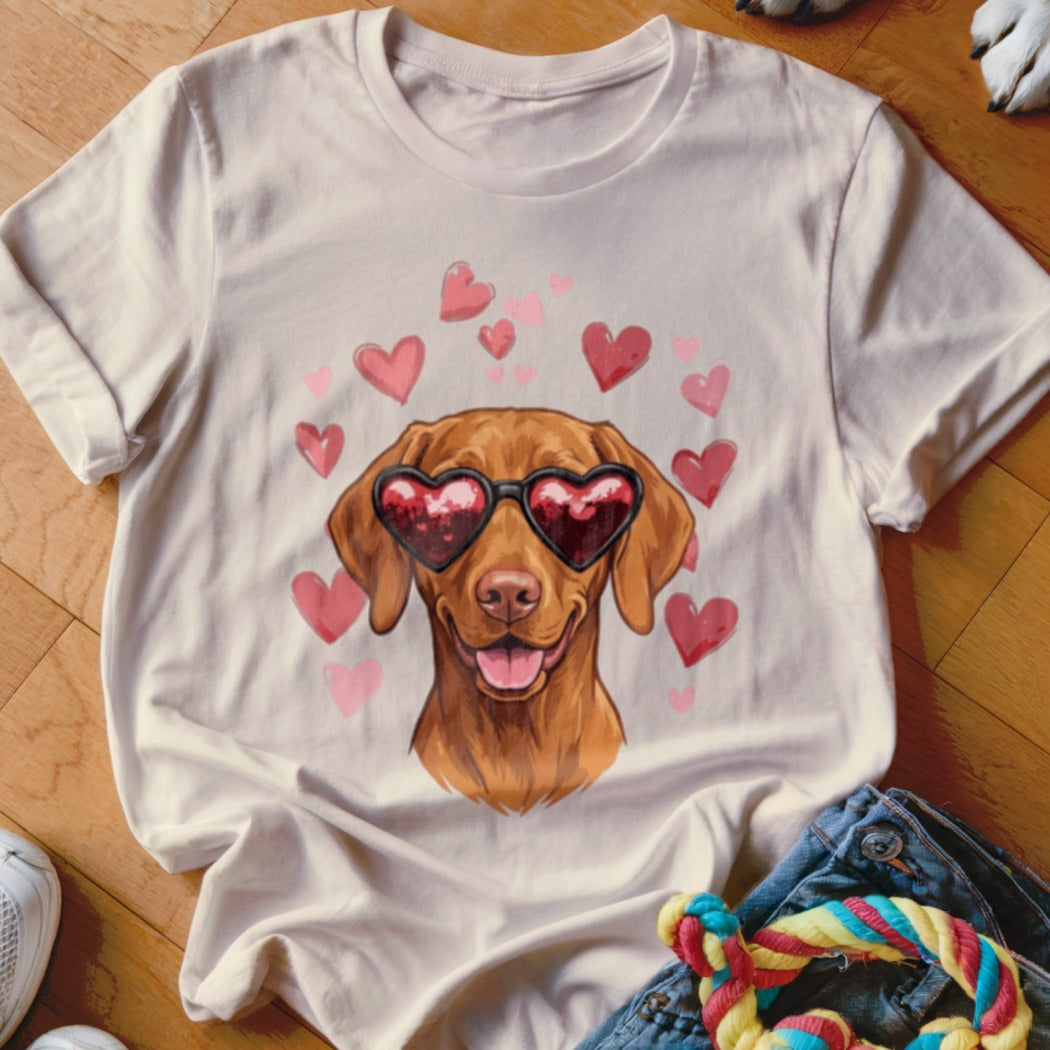 A light-colored t-shirt with a graphic of a brown dog wearing heart-shaped sunglasses, surrounded by pink hearts.