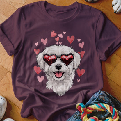 A dark purple t-shirt features a graphic of a white fluffy dog wearing heart-shaped sunglasses surrounded by pink hearts.