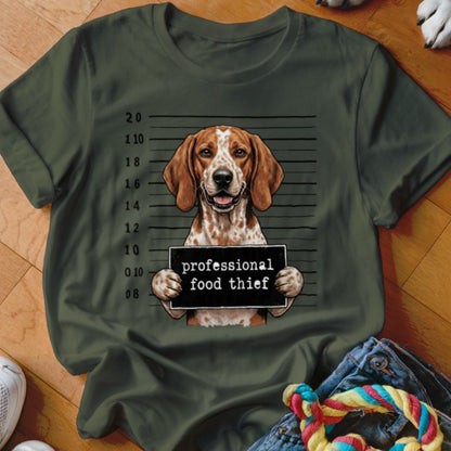 Dog mugshot with "professional food thief" sign on a green t-shirt.