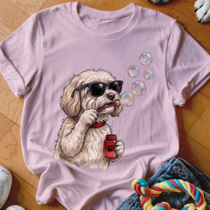 A light pink t-shirt features a graphic of a fluffy white dog wearing sunglasses and blowing bubbles.