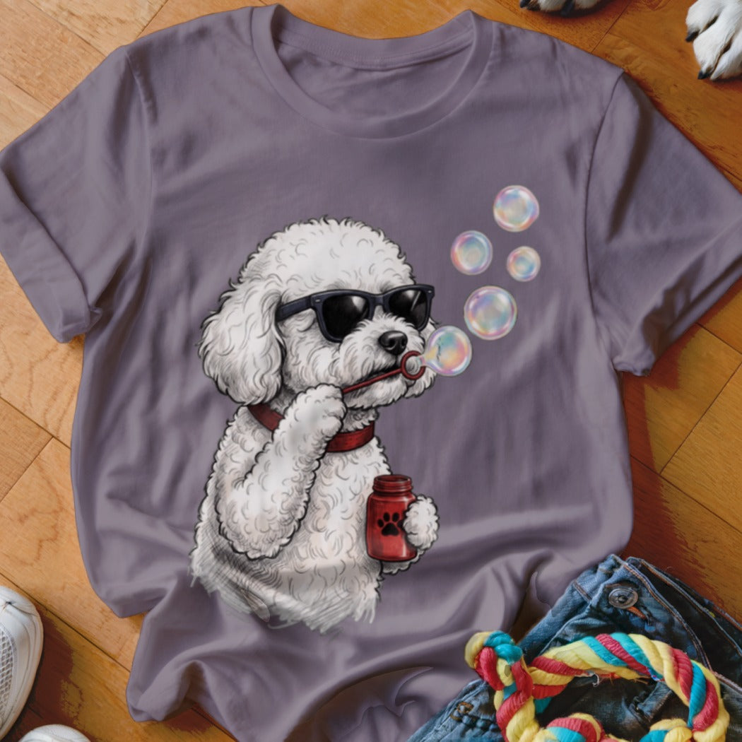A purple t-shirt featuring a graphic of a white poodle wearing sunglasses and blowing bubbles.