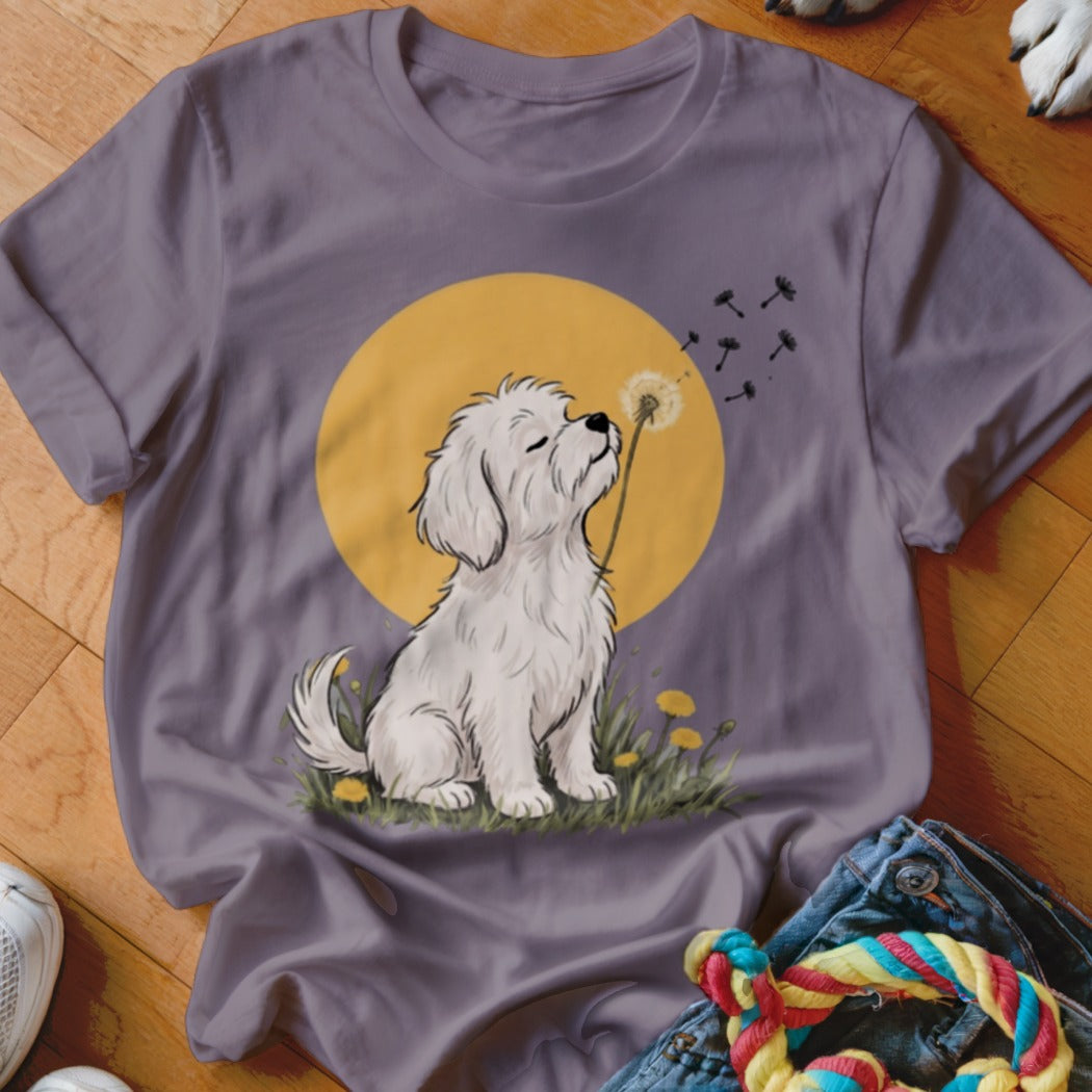 A purple t-shirt featuring an illustration of a white dog blowing a dandelion against a yellow circle.