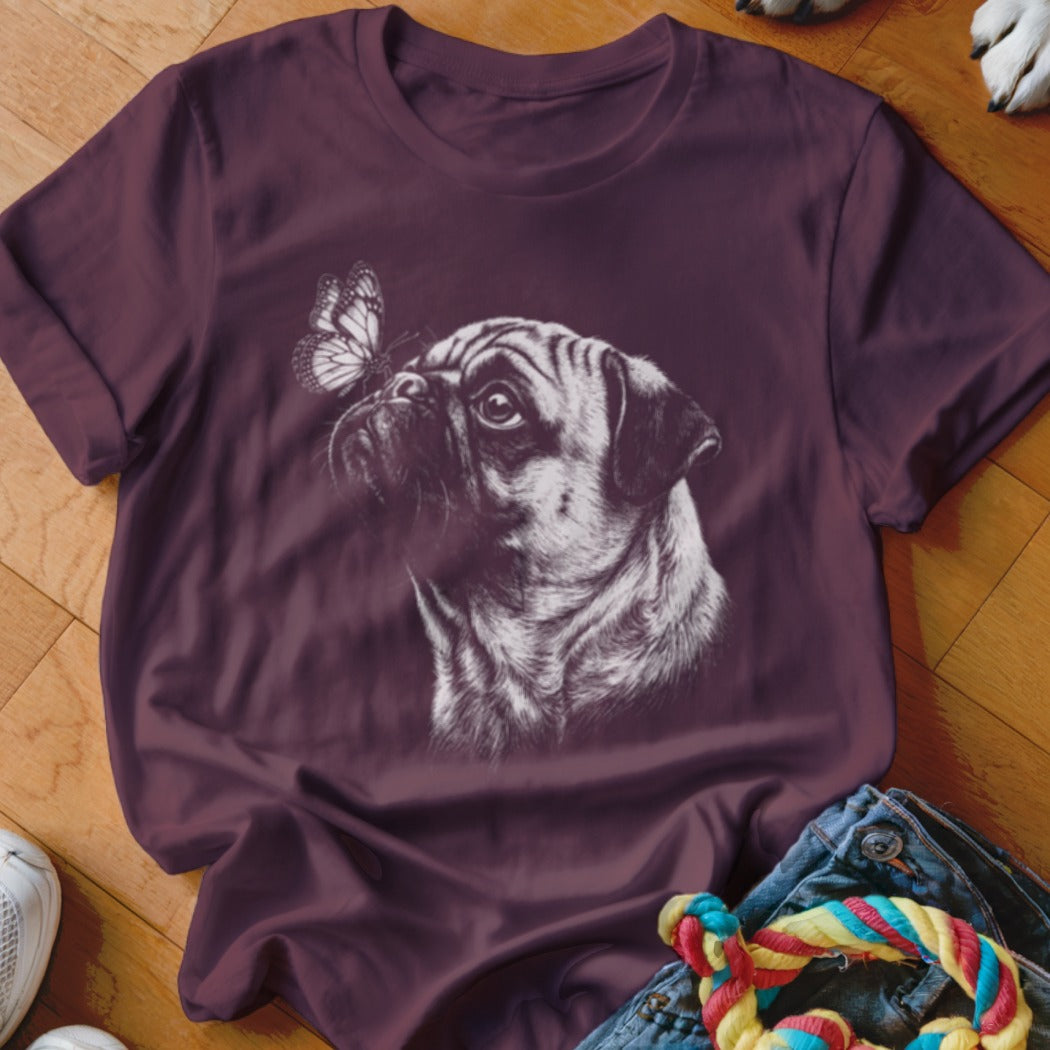 A purple short-sleeved t-shirt features a white sketch of a pug looking at a butterfly.