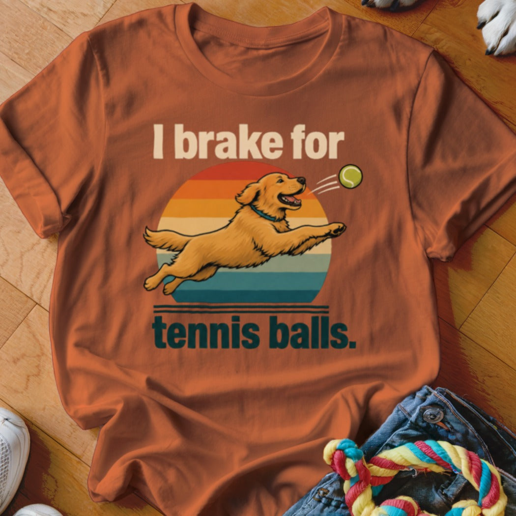 Orange t-shirt with graphic of golden retriever catching tennis ball and text "I brake for tennis balls."