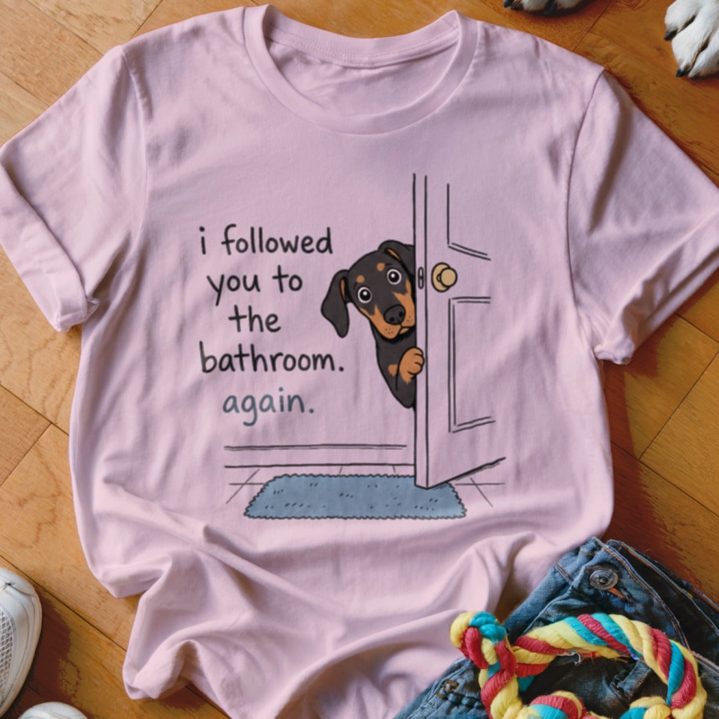 Pink t-shirt with a Dachshund peeking through a door with text "I followed you to the bathroom. again."