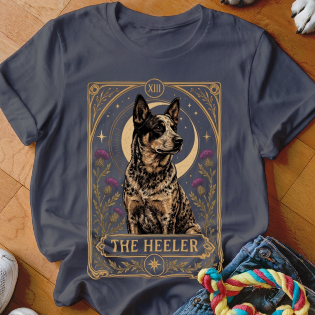 Dark grey t-shirt featuring a tarot card style graphic of an Australian Cattle Dog with purple flowers and the text The Heeler.