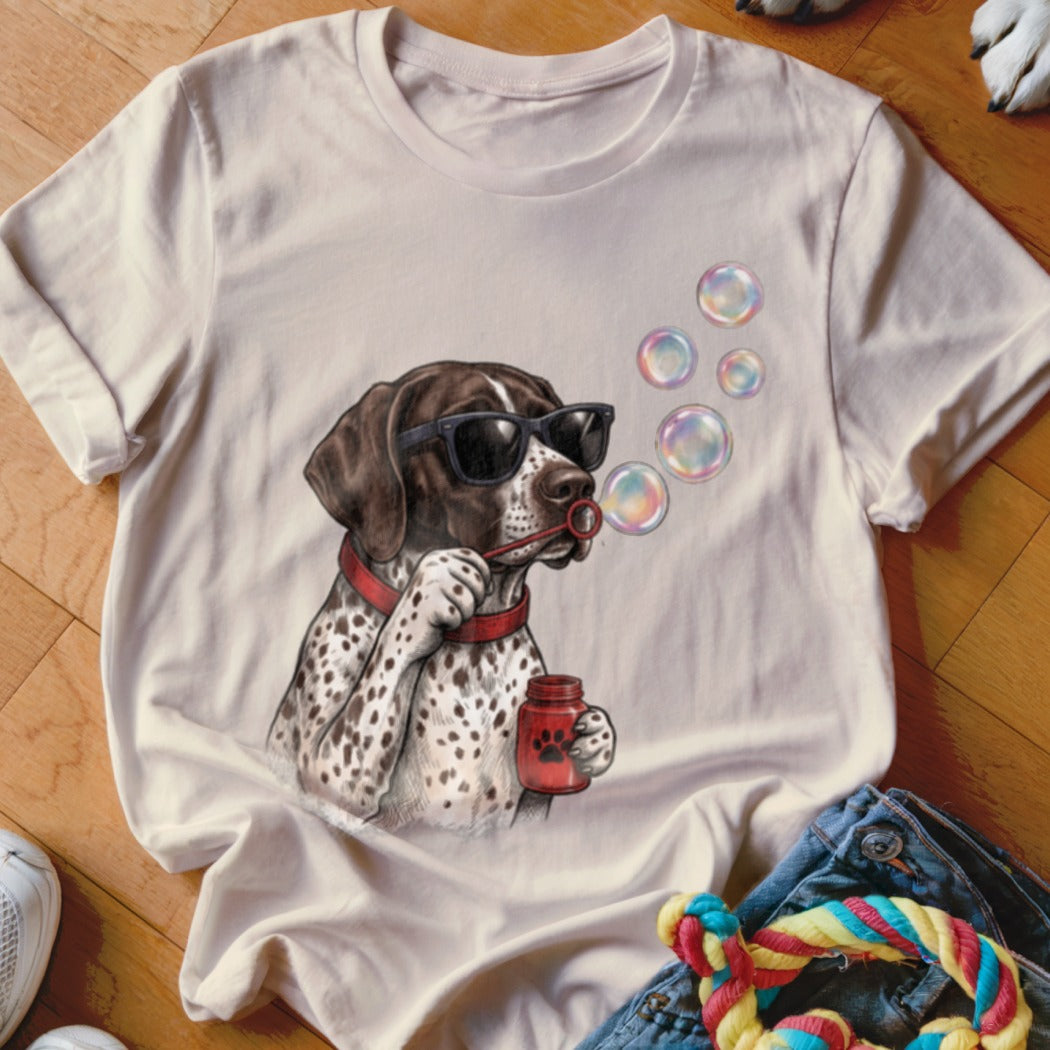 A beige crewneck t-shirt featuring a graphic of a spotted dog wearing sunglasses and blowing bubbles.