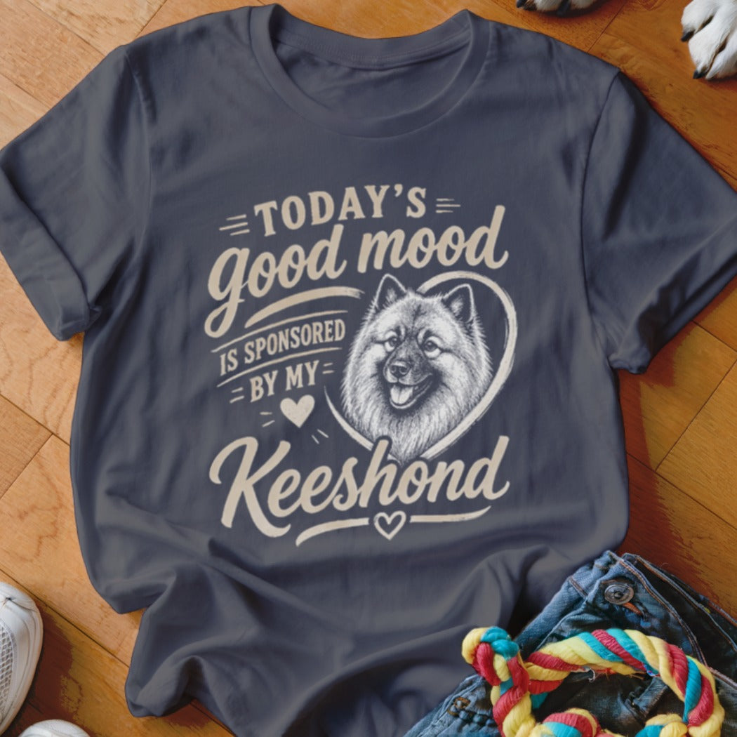 Dark t-shirt with cream text and a Keeshond illustration, reading "Today's good mood is sponsored by my Keeshond."