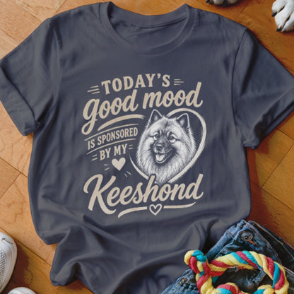 Dark t-shirt with cream text and a Keeshond illustration, reading "Today's good mood is sponsored by my Keeshond."