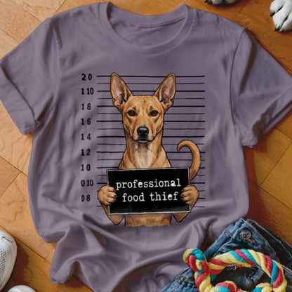 T-shirt graphic of a dog in a mugshot holding a sign that says "professional food thief".