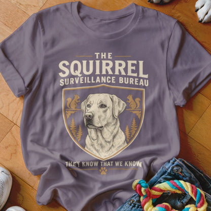 A purple t-shirt featuring a Labrador and text reading The Squirrel Surveillance Bureau.