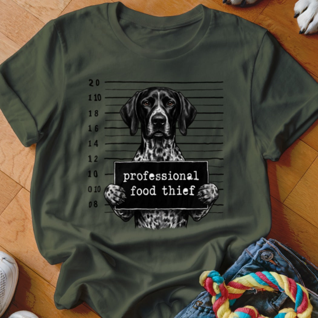German Shorthaired Pointer mugshot with "professional food thief" sign on olive shirt.