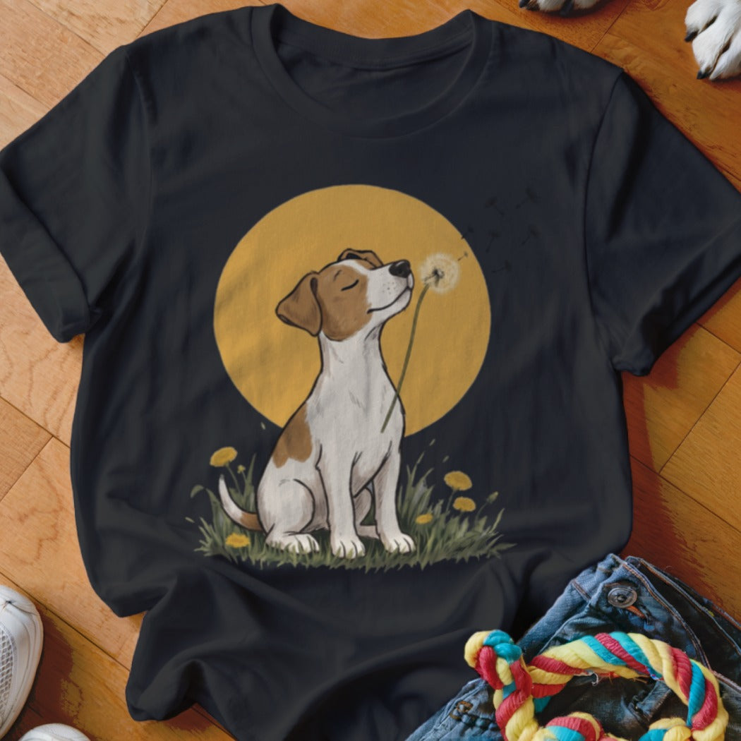 A black t-shirt printed with a graphic of a terrier sitting in grass, blowing dandelion seeds against a yellow sun.