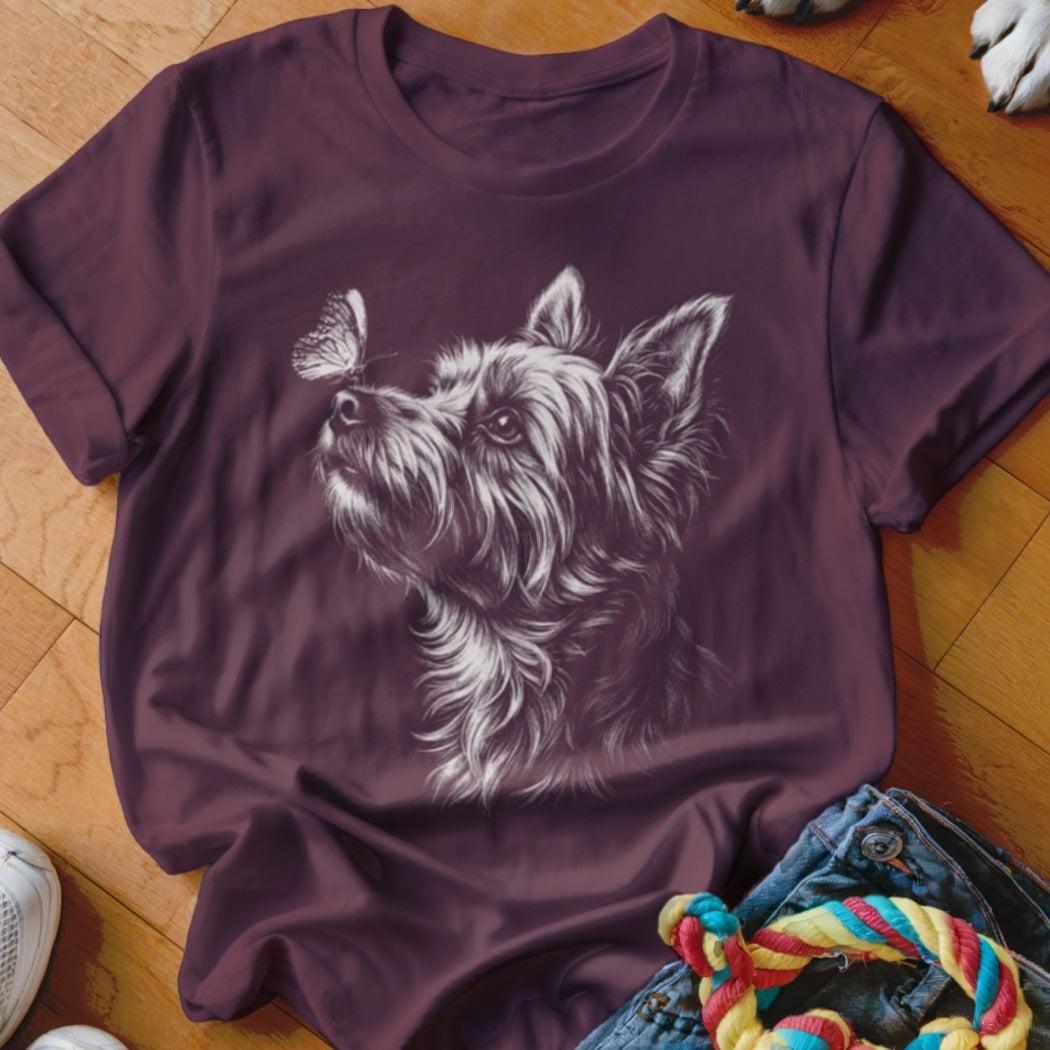 A maroon t-shirt featuring a white sketch graphic of a terrier looking at a butterfly.