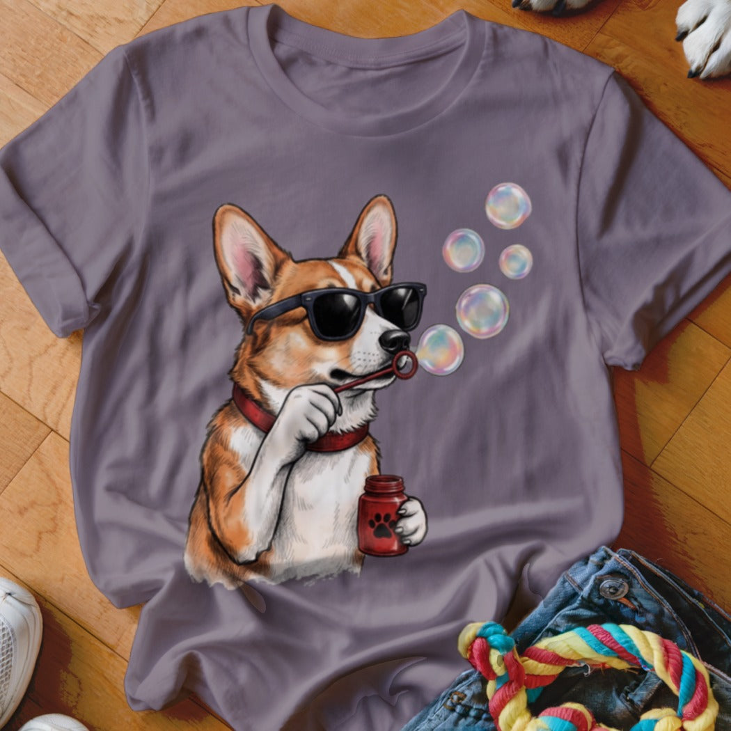 Purple short-sleeve t-shirt featuring a cartoon corgi wearing sunglasses and blowing soap bubbles.