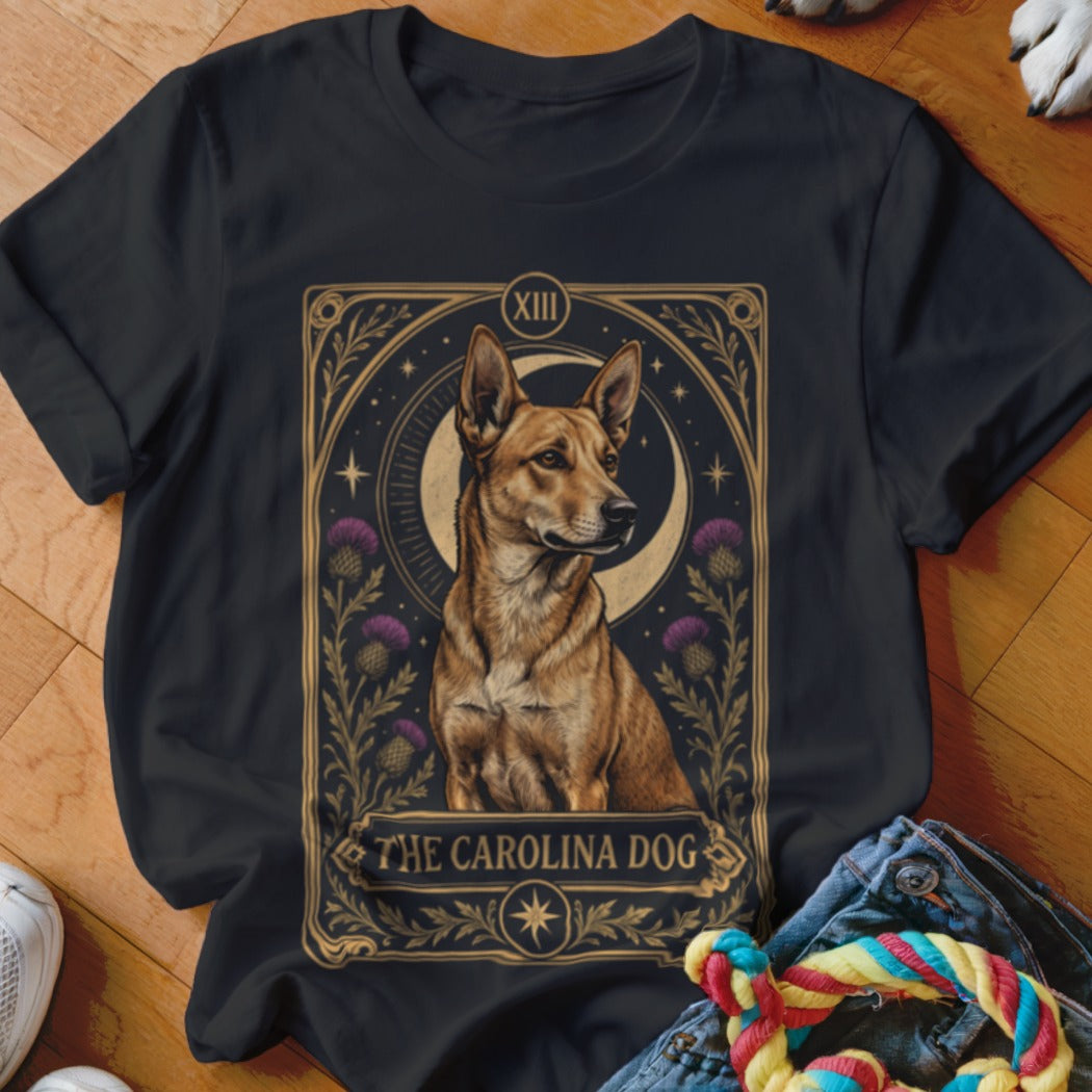 A black t-shirt features a tarot card graphic depicting a Carolina dog framed by thistles and a crescent moon.