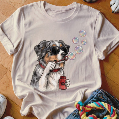 Light beige t-shirt featuring a graphic of an Australian Shepherd wearing sunglasses and blowing bubbles.