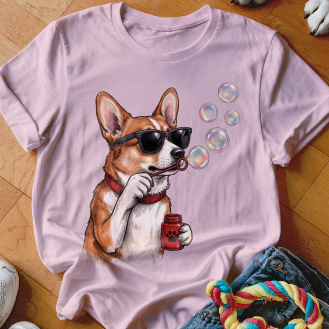Light pink t-shirt featuring a graphic of a corgi wearing sunglasses and blowing bubbles.