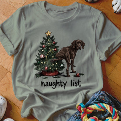 Brown dog peeing on Christmas tree with text "naughty list" on shirt.