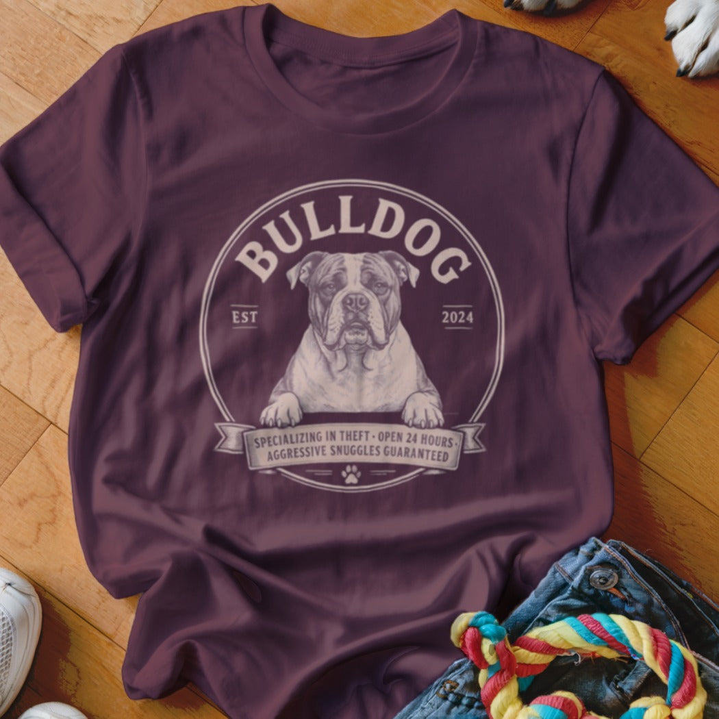 Burgundy t-shirt with a bulldog graphic, text "BULLDOG", "EST 2024", and "AGGRESSIVE SNUGGLES GUARANTEED".