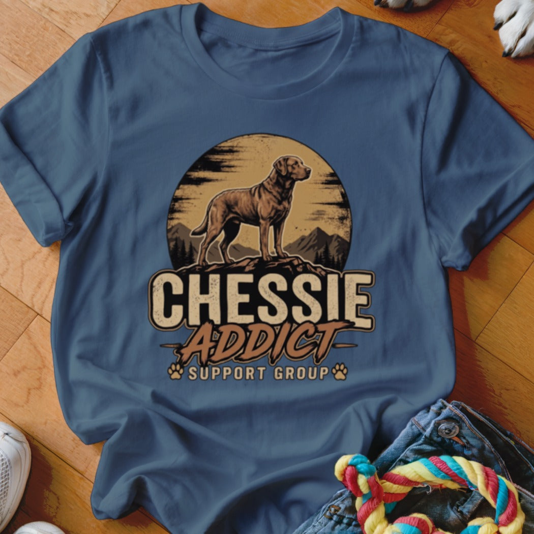 A blue t-shirt featuring a graphic of a dog standing on a mountain with the text Chessie Addict Support Group.