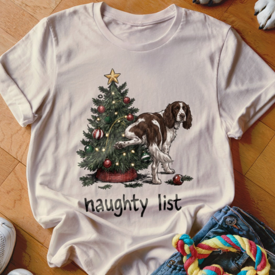 T-shirt with graphic of dog lifting leg on Christmas tree and text "naughty list".