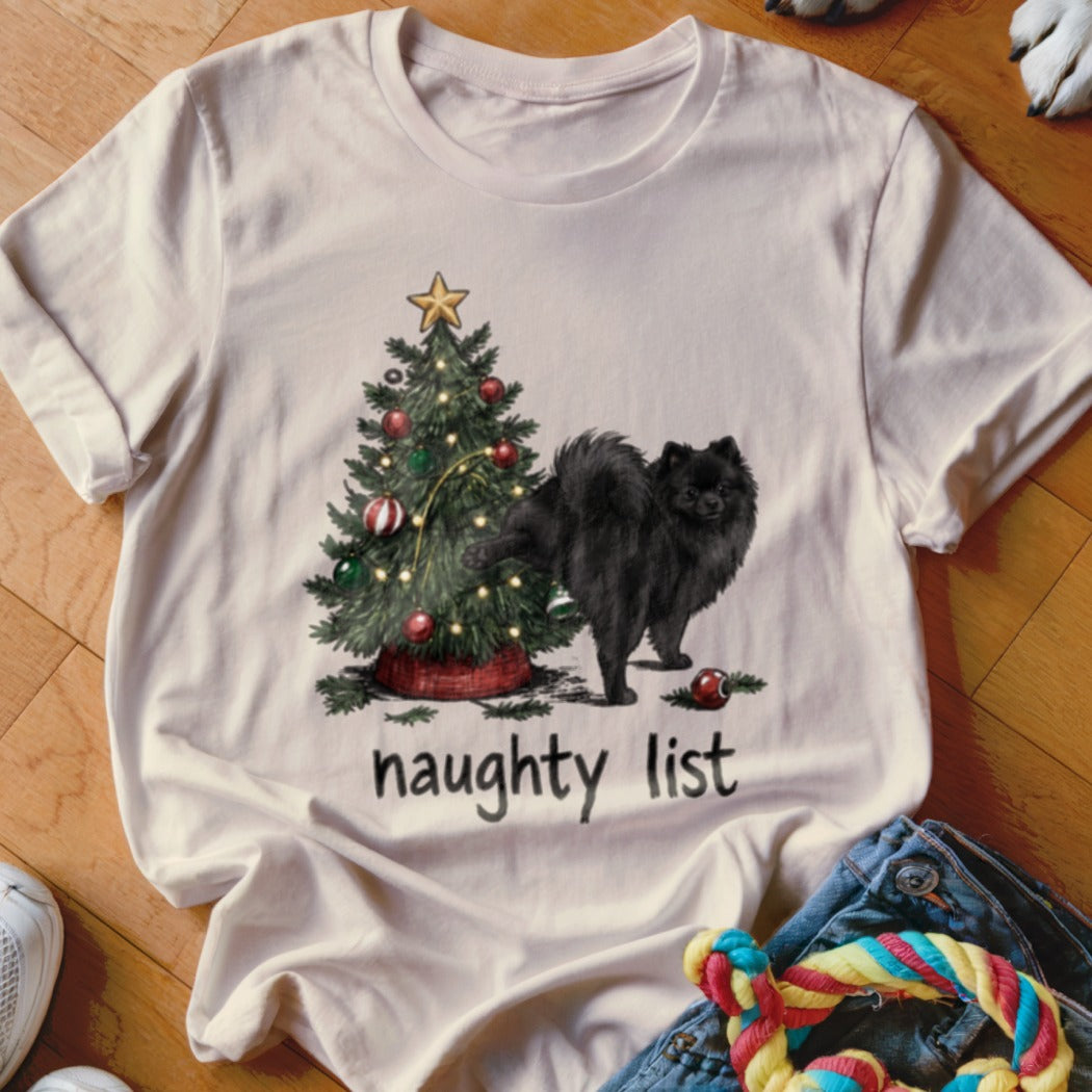 Black Pomeranian dog near a Christmas tree with text "naughty list".