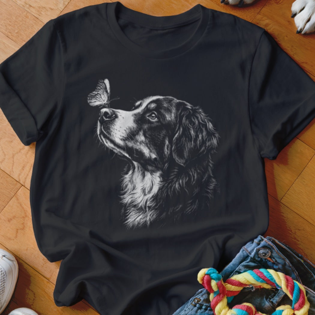 A black t-shirt features a white sketch of a dog looking at a butterfly.