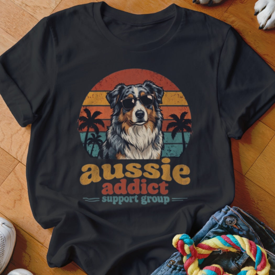 A black t-shirt features a vintage sunset graphic of an Australian Shepherd wearing sunglasses, with text reading Aussie Addict Support Group.